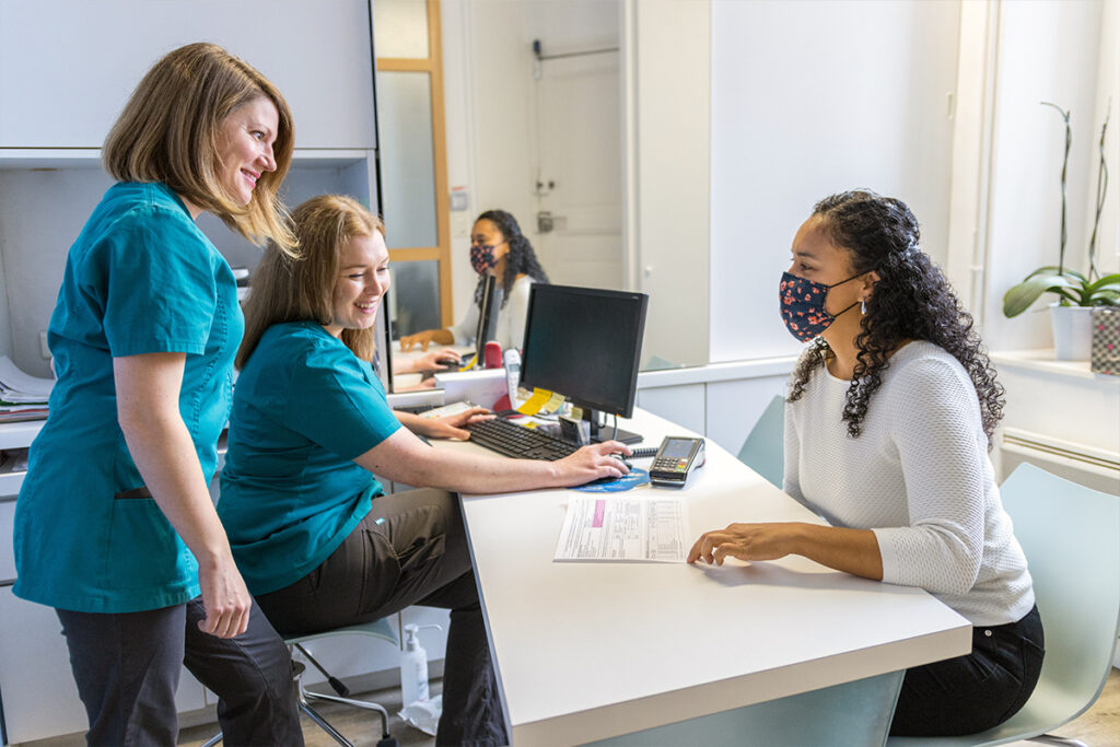 Dental team assisting patient at front desk, reflecting modern dental service organization trends.